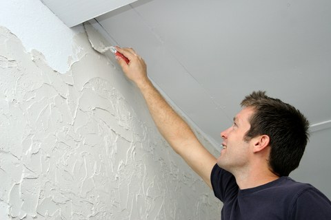 Applying a heavy variation of skip trowel texture to a wall.