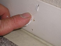 Filling nail holes with spackling paste in interior base trim.