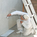 Spraying paint on stucco.